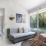 Living area with sofa, rattan chair, and view of the garden.