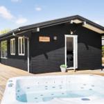 Black wooden house with terrace and outdoor hot tub.