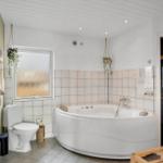 Bad mit Whirlpool, Toilette und Fenster mit getöntem Glas.