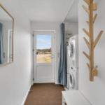 Waschraum mit Waschmaschine, Trockner und Spiegel an der Wand.