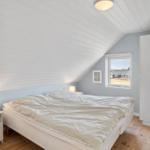 Schlafzimmer mit Dachschrägen, Bett, Fenster und Kleiderschrank.