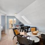 Dachgeschosswohnung mit Tischfußball, Sitzgelegenheiten und Blick auf Balkon.