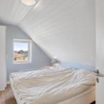 Schlafzimmer mit Dachschräge, Fenster und Bett.
