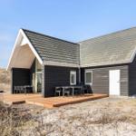Moderne Strandhütte mit Terrasse, Gartenmöbeln und Dachgaube. Ideal für Urlaub an der Küste.