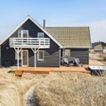 Holzhaus mit Balkon, Terrasse und Whirlpool in trockener Graslandschaft.