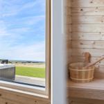 Sauna mit Holzwaschbecken und Blick auf Whirlpool und Landschaft.