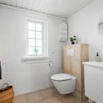 Badezimmer mit Toilette, Waschbecken und Fenster. Wandheizung und Spiegel sind vorhanden.