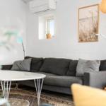 Ein Wohnzimmer mit grauem Sofa, runden Tisch und Wandbildern.