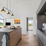 Küche mit Insel, Backofen und Blick auf Wohnbereich mit Kamin.