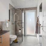 Badezimmer mit Dusche, Waschbecken und Toilette. Moderne Einrichtung mit Glaswand und Spiegelschrank.
