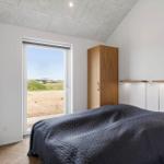 Schlafzimmer mit Bett, Schrank und Fenster zur Außenterrasse.