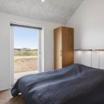 Schlafzimmer mit Bett, Kleiderschrank und Fensterblick auf Außenbereich.