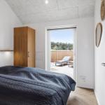 Schlafzimmer mit Balkon, Holzboden und Holzschrank. Blick auf Wald.