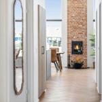 Haus mit Kamin, Holzfußboden und Blick auf Terrasse.