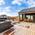 Terrasse mit Whirlpool, Liegestühlen und Grillbereich. Holzdeck und Sicht auf die Umgebung.