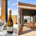 Bottle of champagne and glasses on tray. Wooden terrace with table, chairs, and grill.