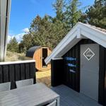 Terrasse mit Tisch und Stühlen, Sauna und kleines Haus mit Tür.