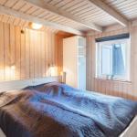 Schlafzimmer mit Holzwand, weißem Bett und Fenster mit Pflanzen.