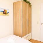Schlafzimmer mit Bett, Kleiderschrank und Wandbild.