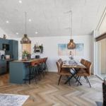 Küche mit Essbereich, Holzboden und Kamin. Moderne Einrichtung mit braunen Stühlen.