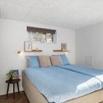 Schlafzimmer mit Bett, Fenster und Schiebetür. Wandregale und kleine Tischlampe.