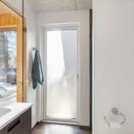Badezimmer mit Waschbecken, Spiegel und Tür zum Außenbereich.