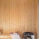 Sauna mit Holzwand, Sitzbank, Körbchen und Heizung.