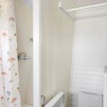 Shower with floral curtain and washing machine with basket.