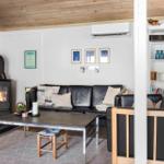 Living room with sofa, fireplace, and table. Shelf and ceiling made of wood.