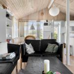 Living area with black leather sofas, wooden floor, and kitchen area in the background.