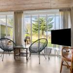 A living room with large windows, two chairs, and a TV.