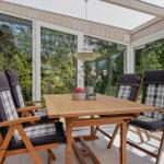 Holztisch mit vier Stühlen und Plaidbezug im Innenhof mit Glaswänden.