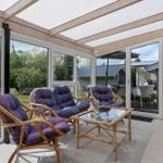 Terrasse mit Sitzgruppe und Glasdach. Blick auf Garten und angrenzende Häuser.