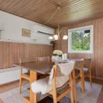 Esszimmer mit Holzwand, Tisch, Stühlen und Fenster zum Garten.