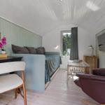 Schlafzimmer mit Bett, Schreibtisch, Sessel und Fernseher an der Wand.