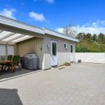 Haus mit überdachter Terrasse, Grill und Pflanzen im Garten.