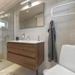 Bad mit Dusche, Waschbecken und Toilette. Wandhalterung und Spiegel sichtbar.