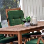 Holztisch mit grünen Sitzkissen und zwei Weingläsern auf einer Terrasse.