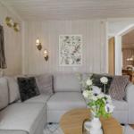 Wohnzimmer mit grauem Sofa, Holztisch und Blumen. Küche und Essbereich sind sichtbar.