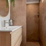 Badezimmer mit Waschbecken, Spiegel und Dusche. Wandfarbe in Terrakotta-Tönen.