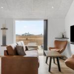 Living room with sofa, chairs, table, and TV. Doorway to terrace with wooden railing.