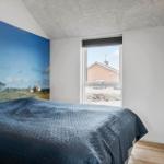 Bedroom with bed, lighthouse mural, and view of a house through window.