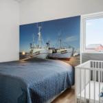Bedroom with bed, crib, and wall mural of fishing boats.