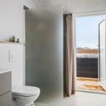 Bathroom with shower, toilet, and view of balcony with hot tub.