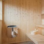 Sauna with wooden walls, bench, and heater