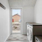 Entrance area with washing machine, door to outdoor area, and coat hooks on the wall.