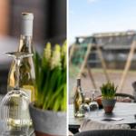 Table with wine glasses, bottle, and plant. Outside view shows balcony seating.