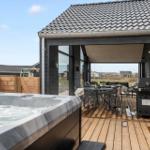 Deck with hot tub, grill, and seating under cover.