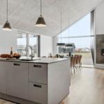 Modern kitchen with island, dining area, and fireplace. Large windows with outdoor view.