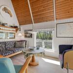 Wohnzimmer mit Sofa, Tisch und Sessel unter Holzdecke.